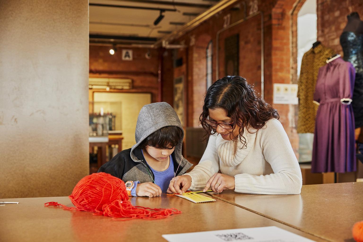 An adult helps a child with a craft activity at the Museum of Making in Derby.
