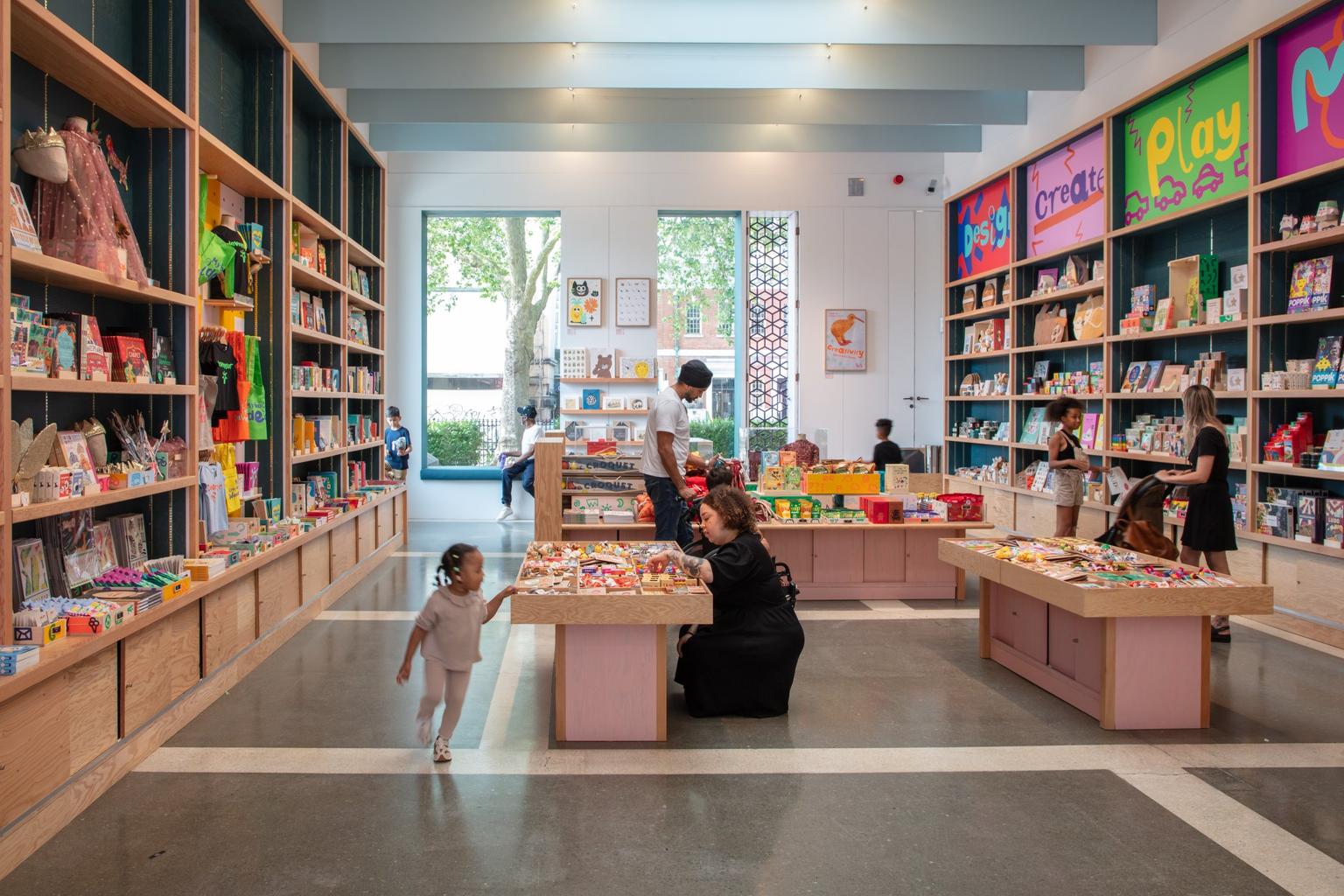 People browsing colourful shelving and display tables in the Young V&A shop