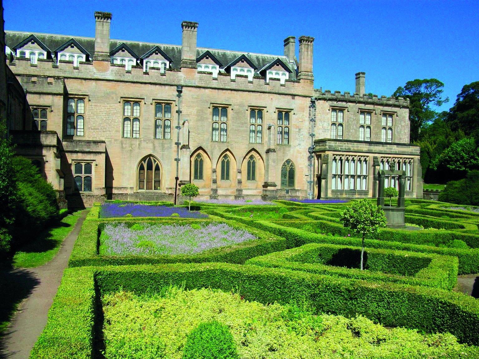 A historic house fronted by ornamental gardens with box hedges