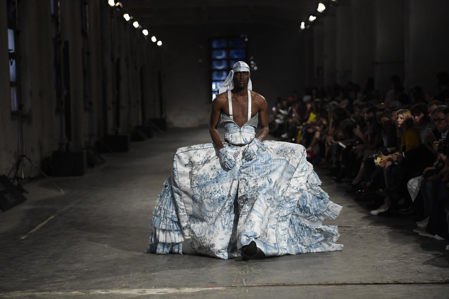 A model walking the catwalk in a Regency style dress held up with suspenders