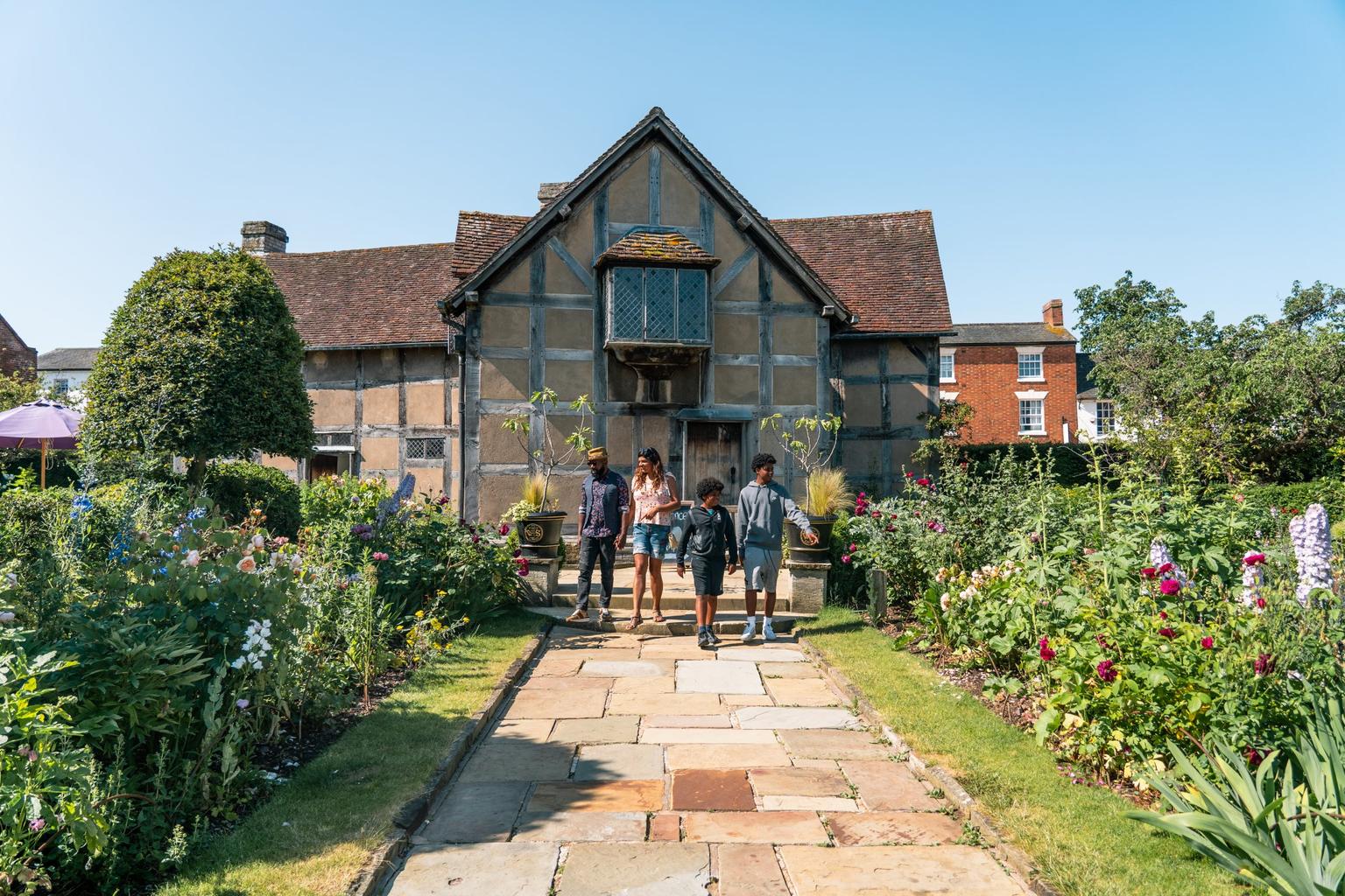A family of four walking down the stone path in front of Shakespeare's Birthplace