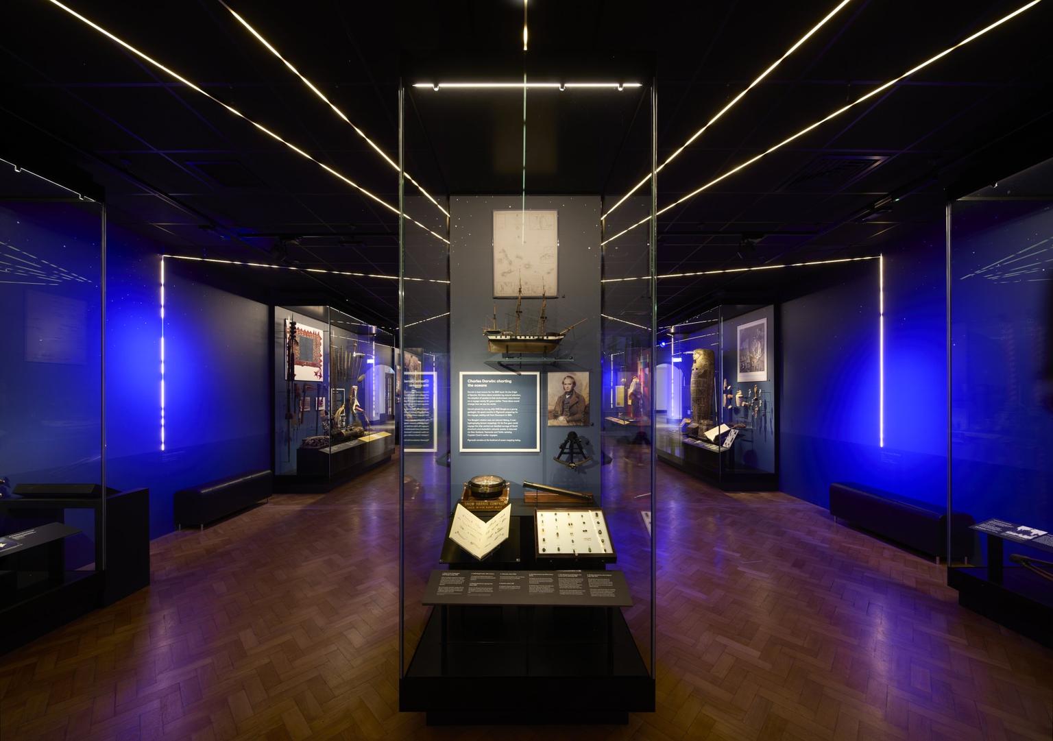 A museum gallery with purple lighting and objects in cases