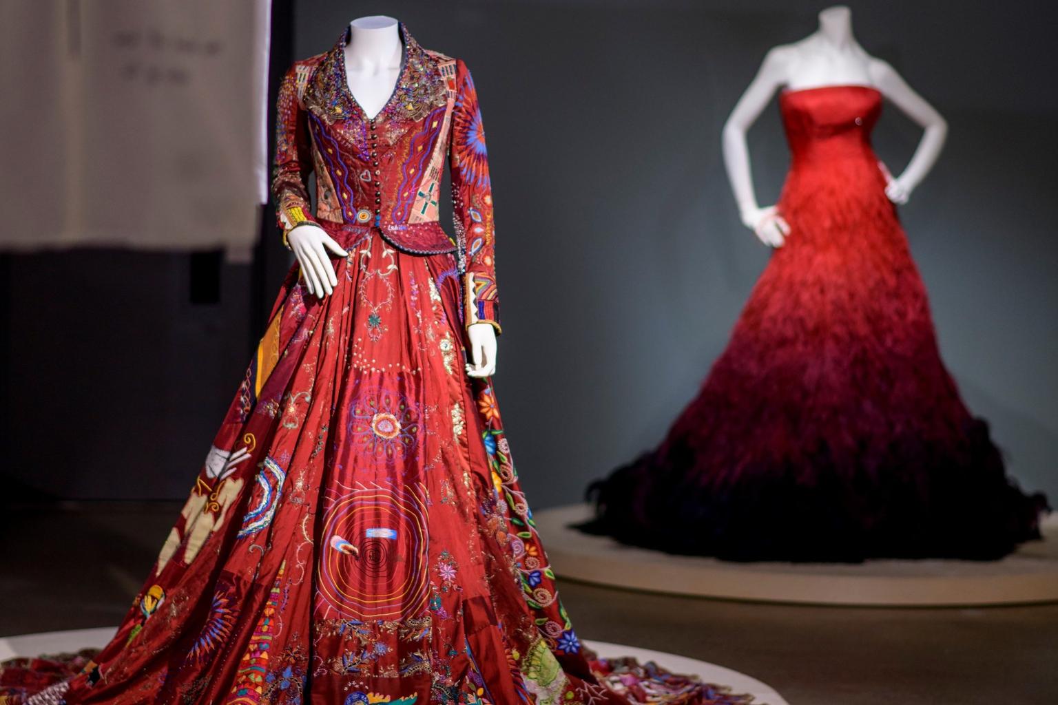 A red embroidered dress in the foreground, with a strapless red evening dress in the background