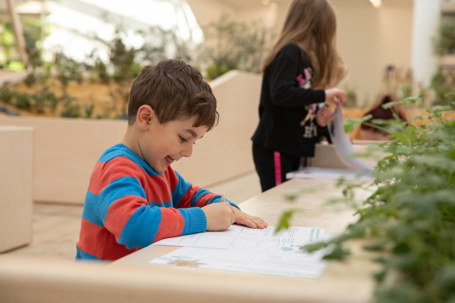 A boy smiles as he fills in an activity sheet