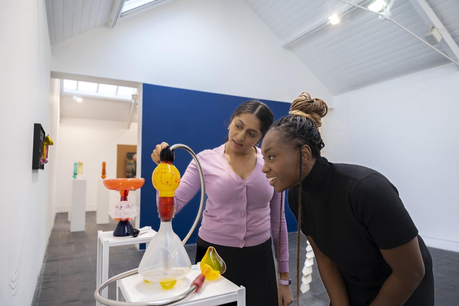 Visitors smile while examining a colourful sculpture