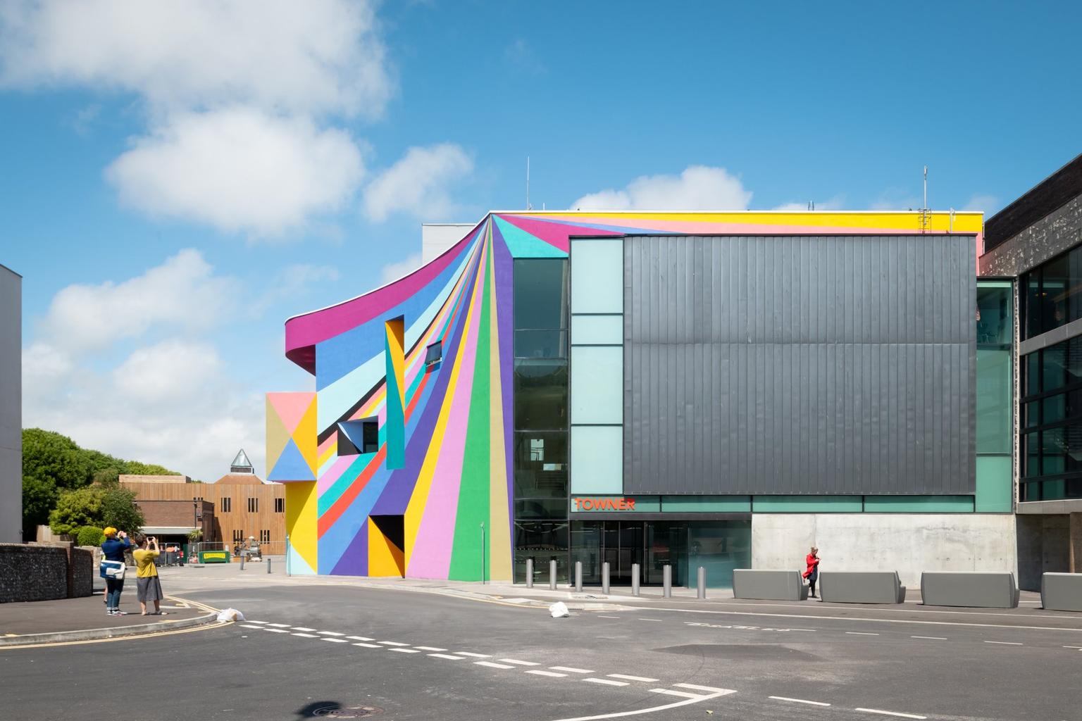 A photograph of a colourful striped building from across a road