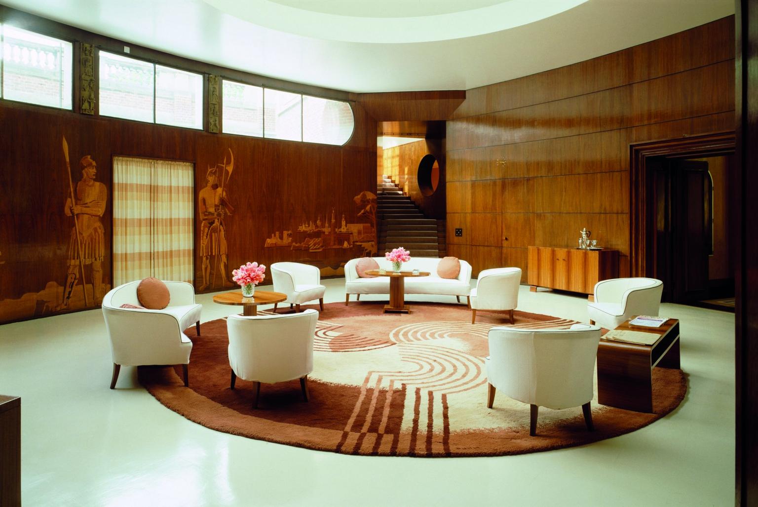An art deco room at Eltham Palace with panelled walls and a circular rug