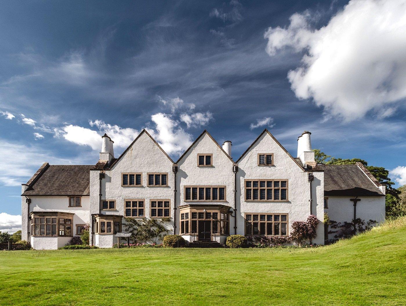 A white washed house fronted by a lawn, with blue skies above
