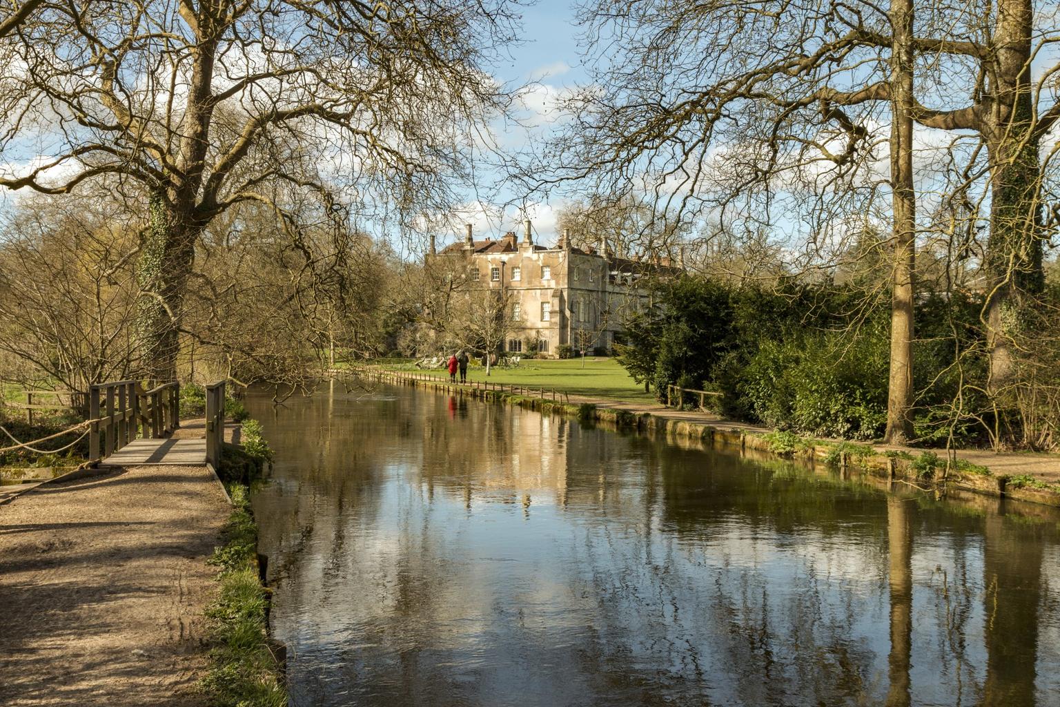 View of a river and towpath with a grand house in the distance