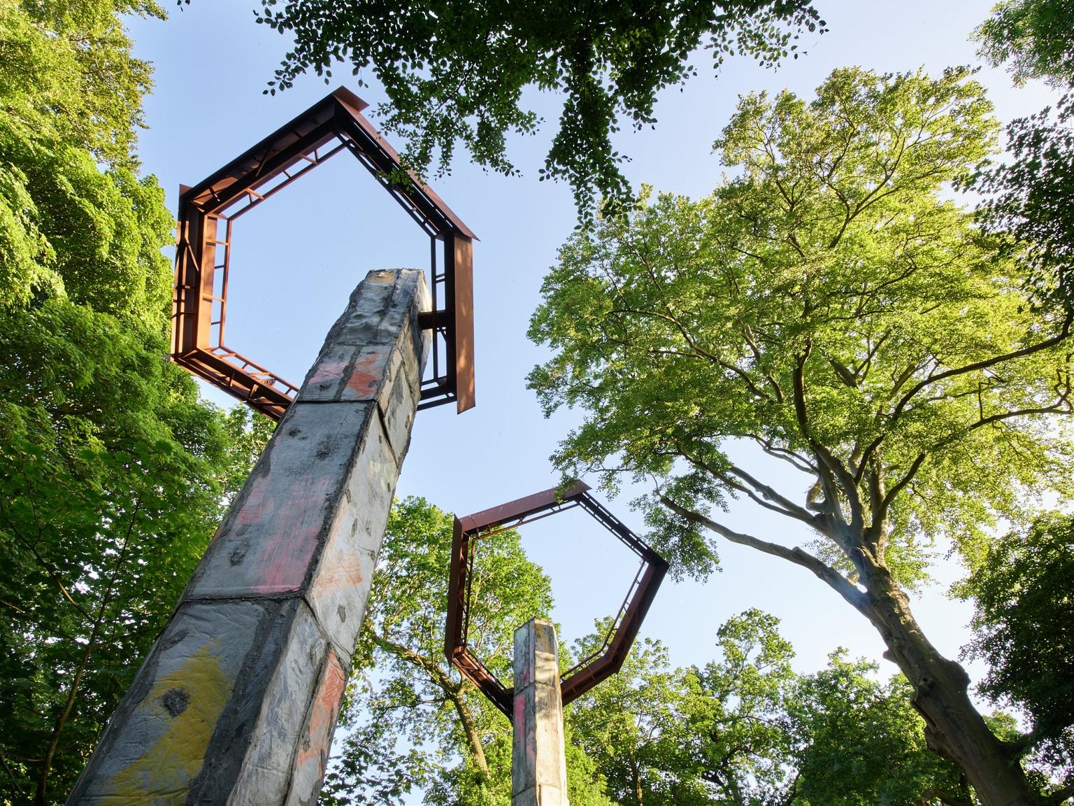 Pilon-like structures topped with metal hexagons, in amongst trees