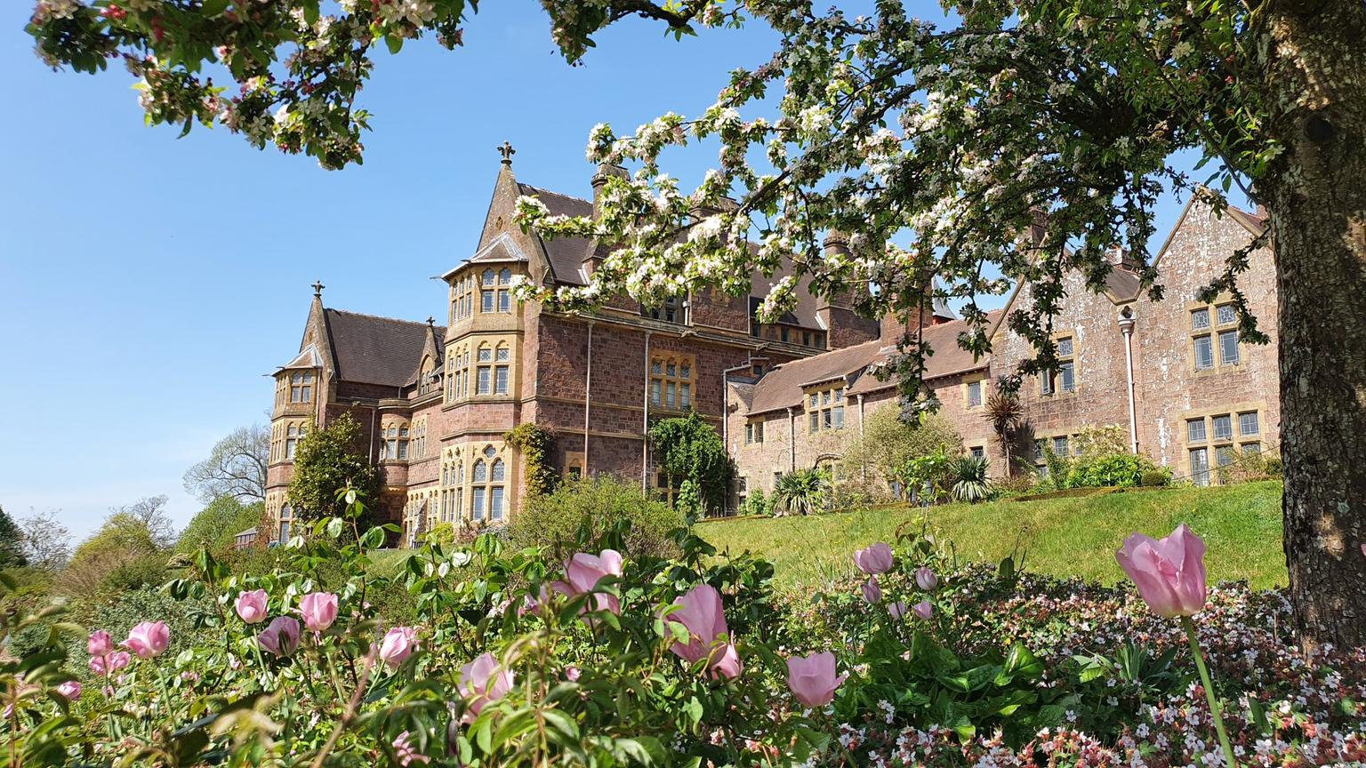 An ornate Victorian House fronted by flower beds