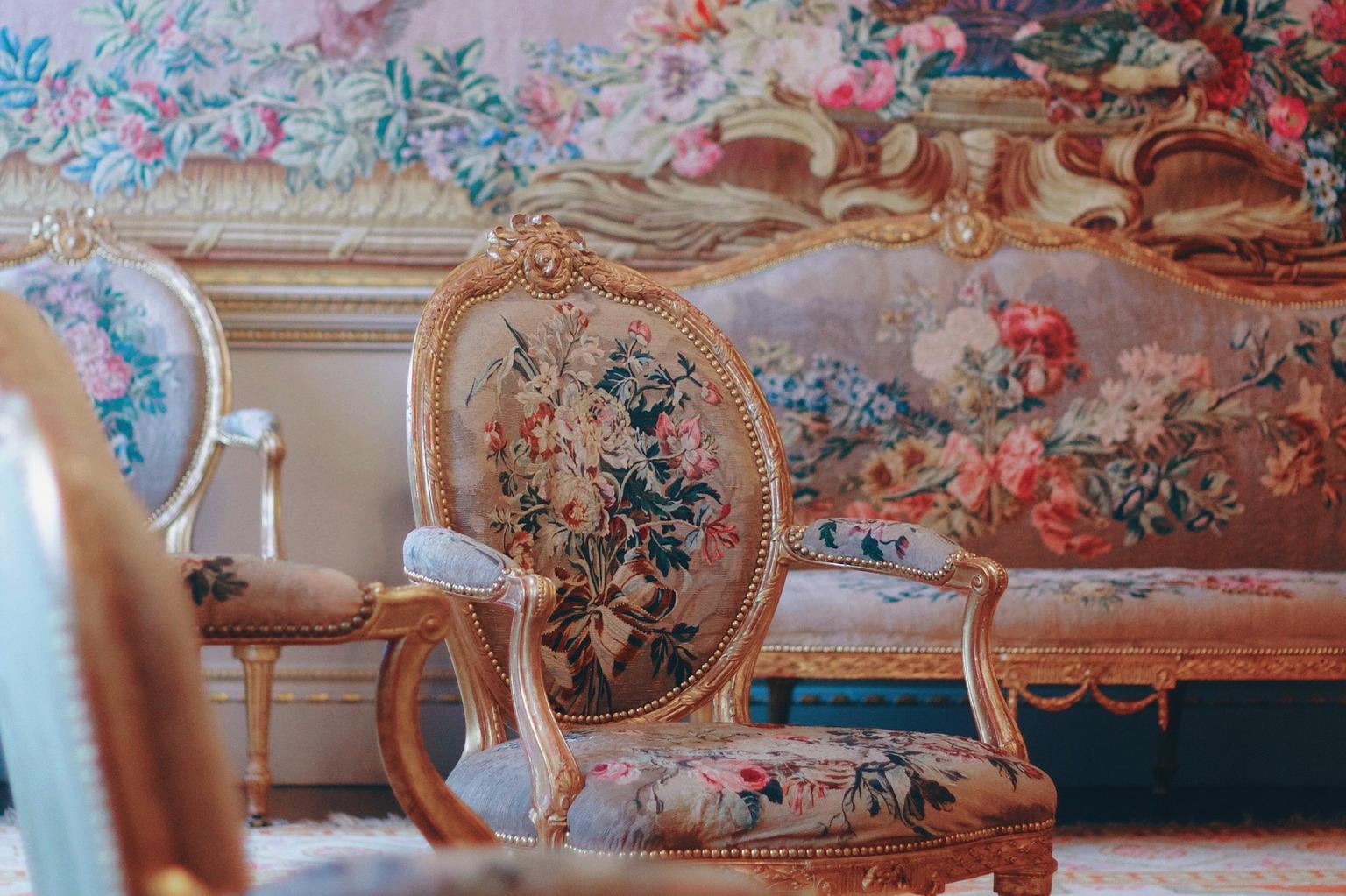 A chair, sofa and tapestry in a paisley pink print