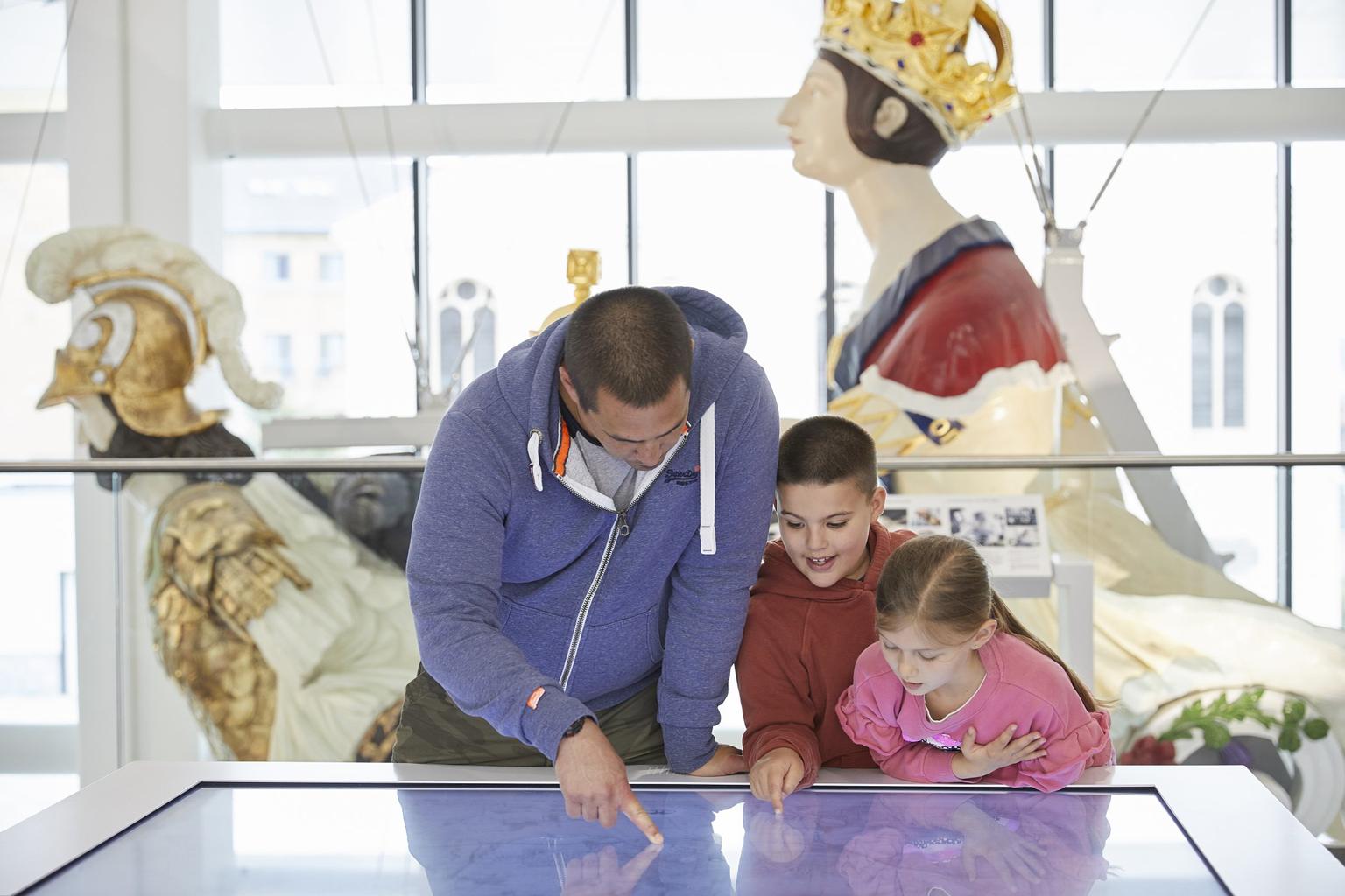 A familisy touch an interactive display screen in a gallery