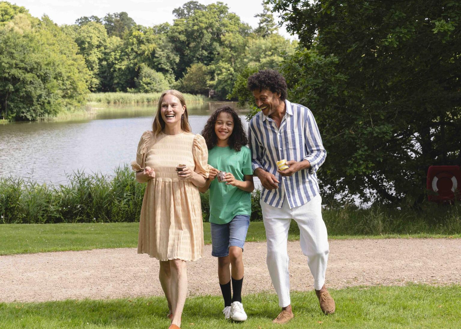 A woman, man and young girl walking across the lawn in a countryside park