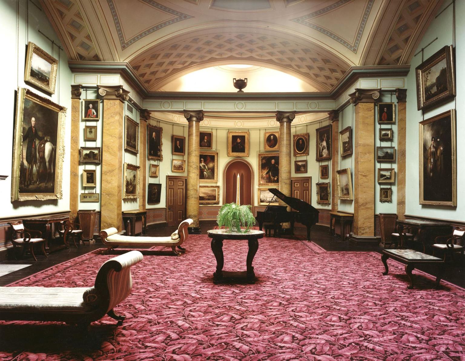 An ornate picture gallery with patterned carpet and marble columns