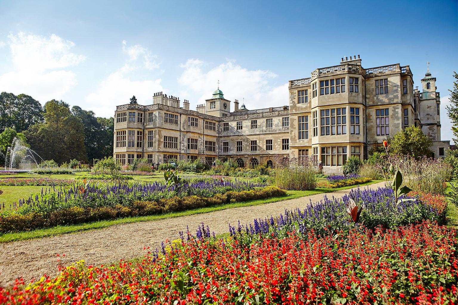 Ornamental gardens with a fountain in front of a three storey mansion