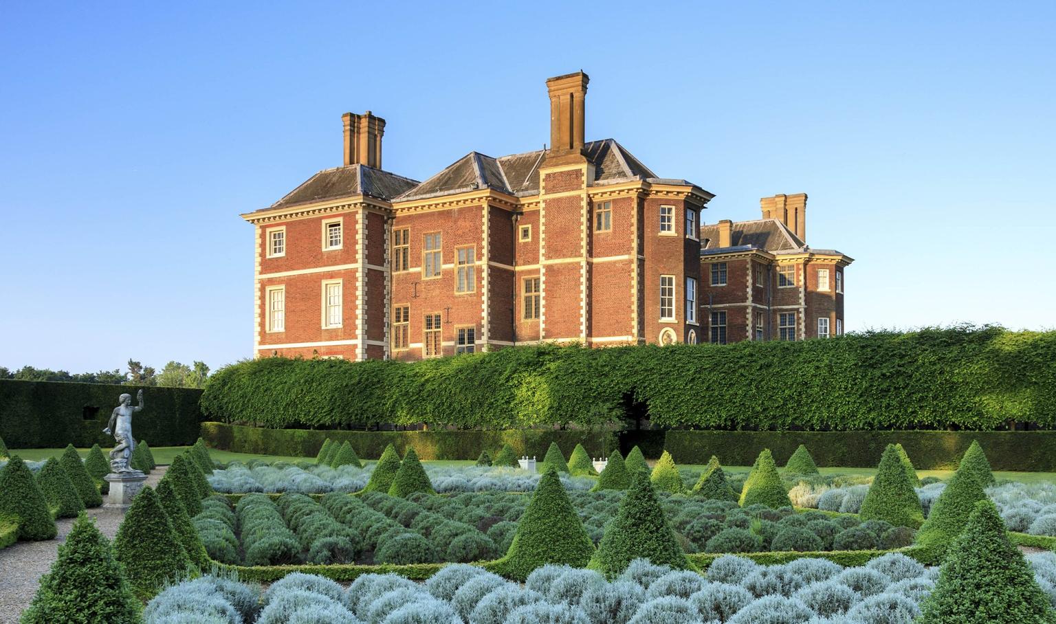 Sunrise over a stately house, with formal gardens in the foreground