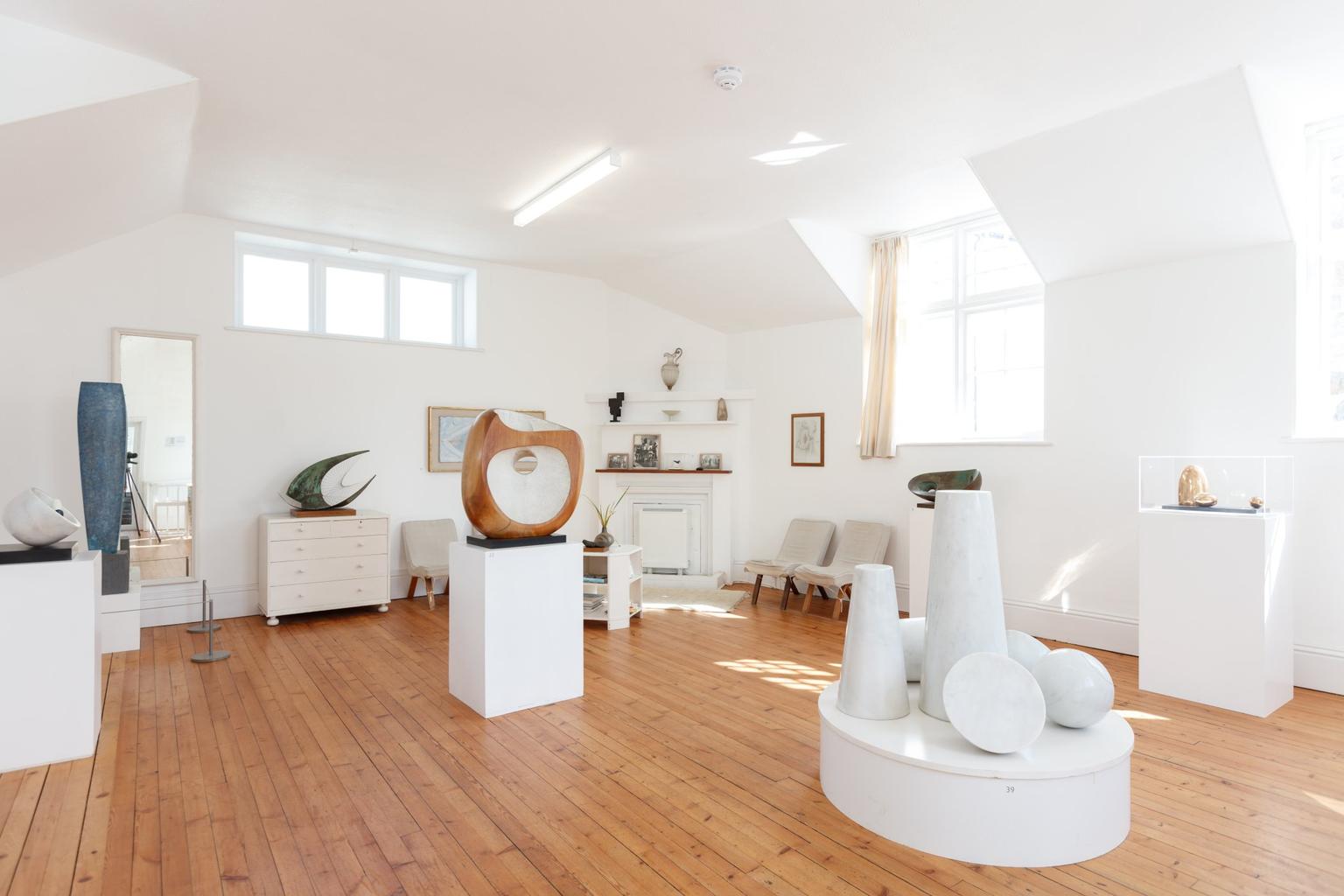 A white walled gallery dotted with sculptures