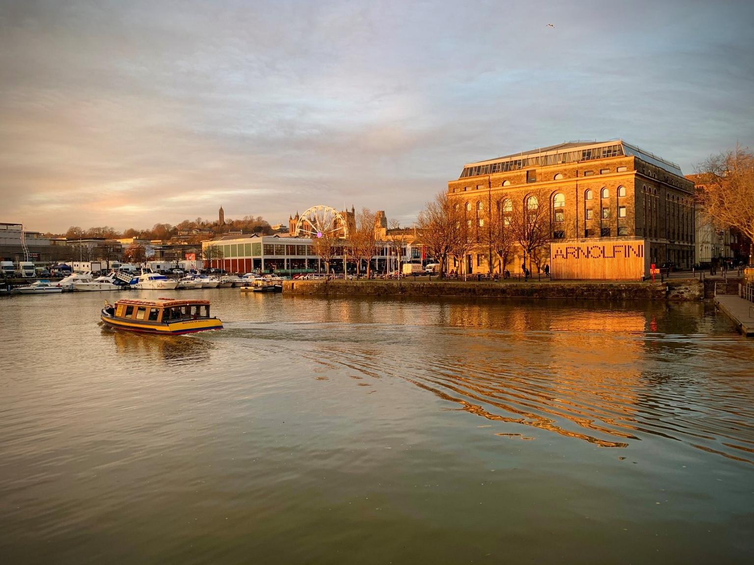 A gallery building seen across some water at sunset