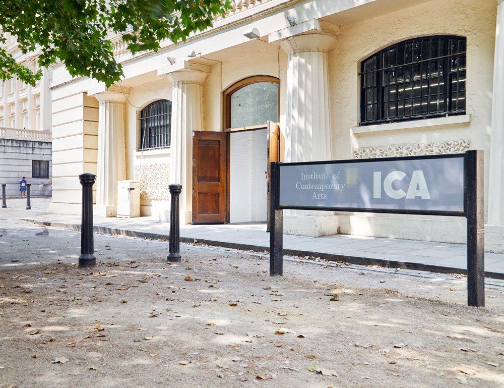 The entrance to the Institute of Contemporary Arts in London, a neo-classical building with stone columns. Its wooden front doors are open; the glass above the door displays its logo.