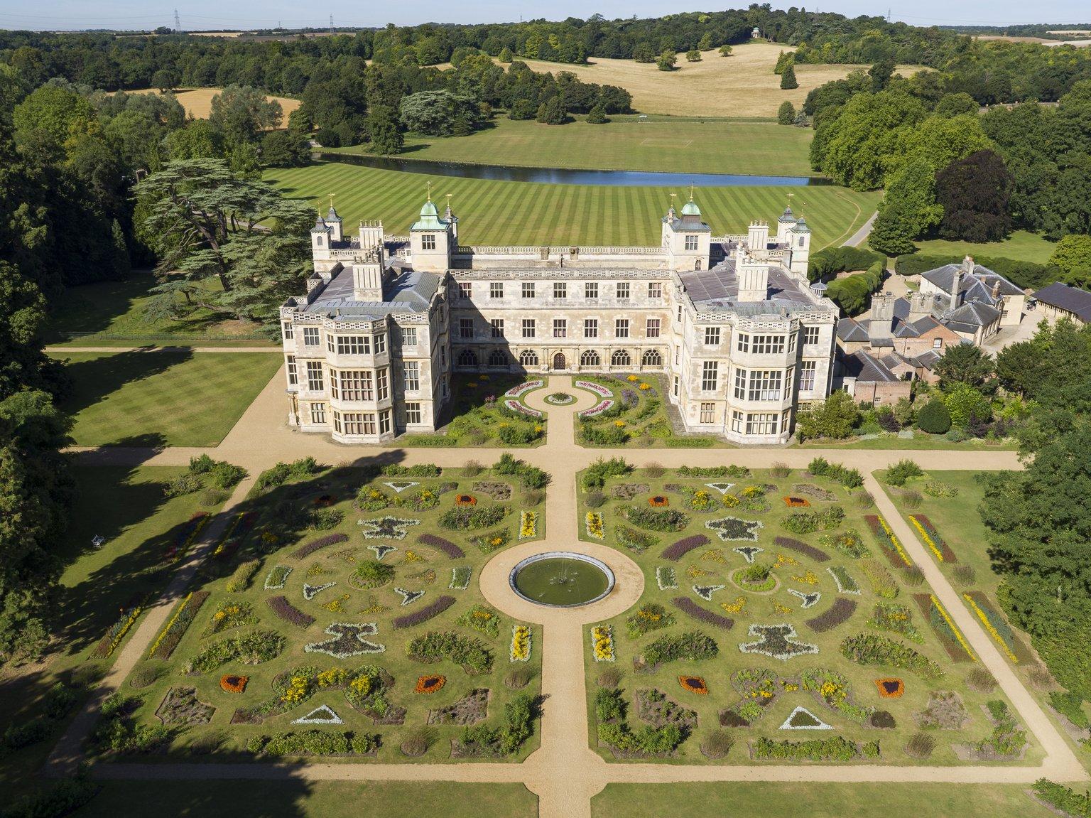 An aerial shot of ornamental gardens in front of a stately house