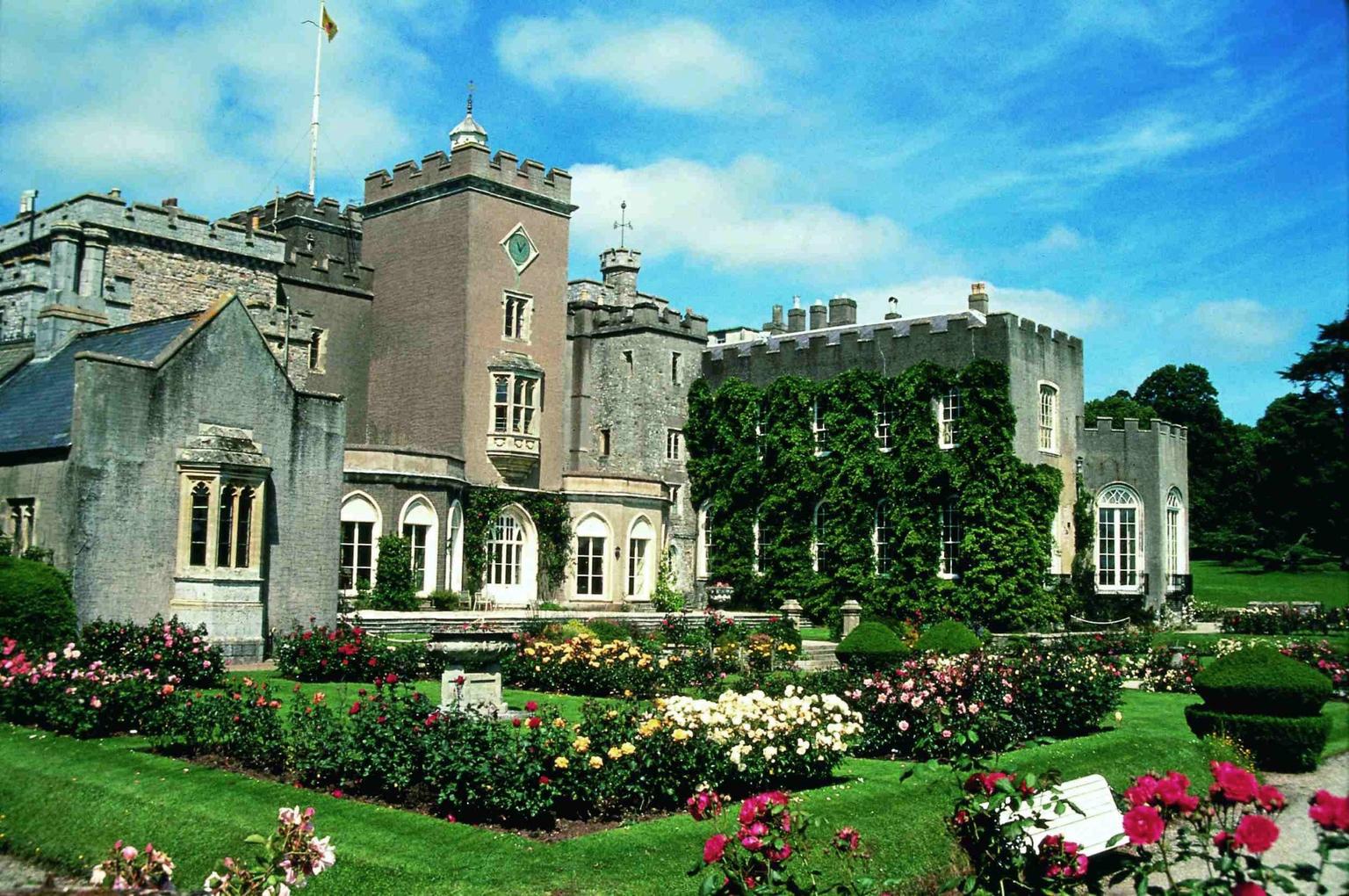 Rose gardens in the foreground of a castle, blue skies above