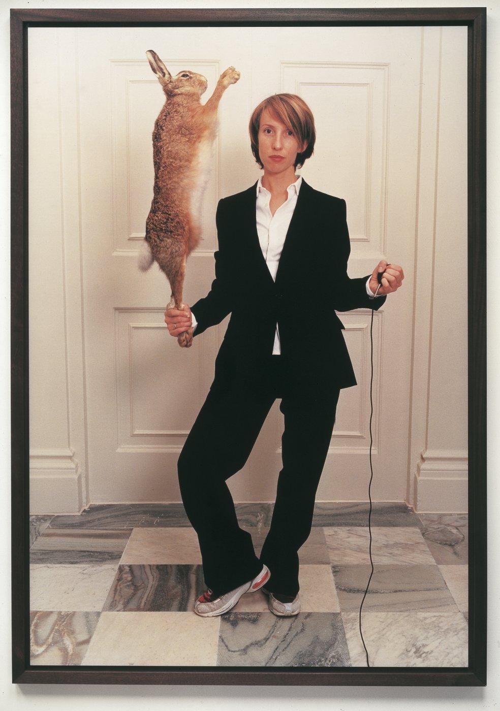 This self portrait documents a significant moment in the artist's life: her recent battle with a second occurrence of cancer, which resulted in a mastectomy. The artist captures herself in a frozen moment, confronting her mortality holding the cable release of her camera and a stuffed hare. Taylor-Johnson explained: 'The hare symbolises lust and passion, so here I am with a head of hair, in a single-breasted suit, holding on to lust and passion.'