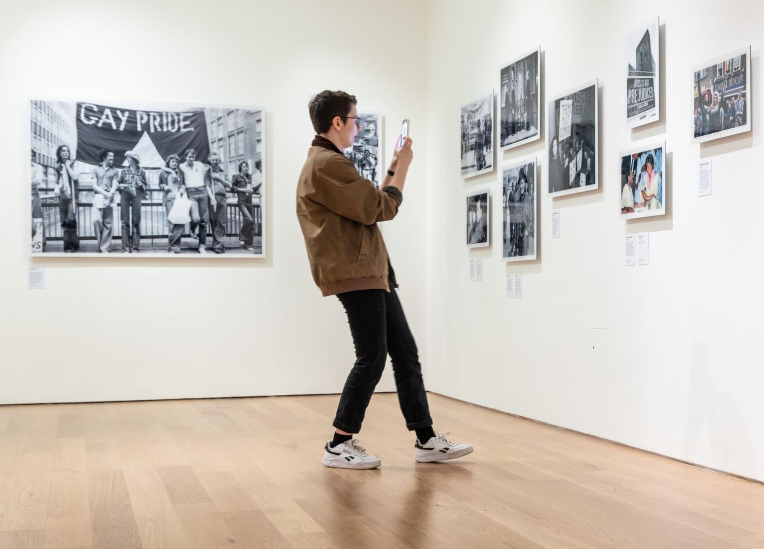 A man leans back to take a photograph of an image in an exhibition