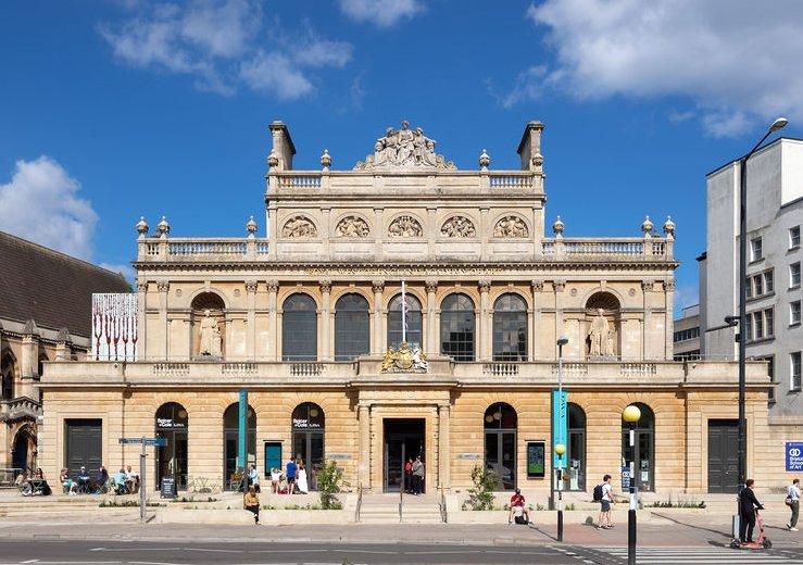 A grand Italianate limestone three-story building, adorned with neoclassical columns and statues.