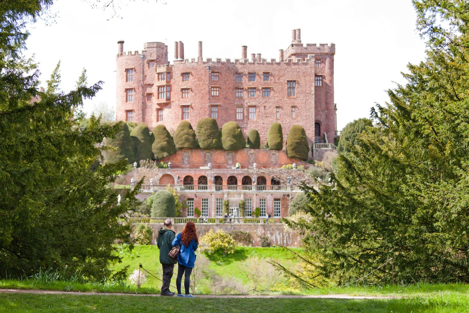 Two people in the foreground looking at Powis Castle and grounds.