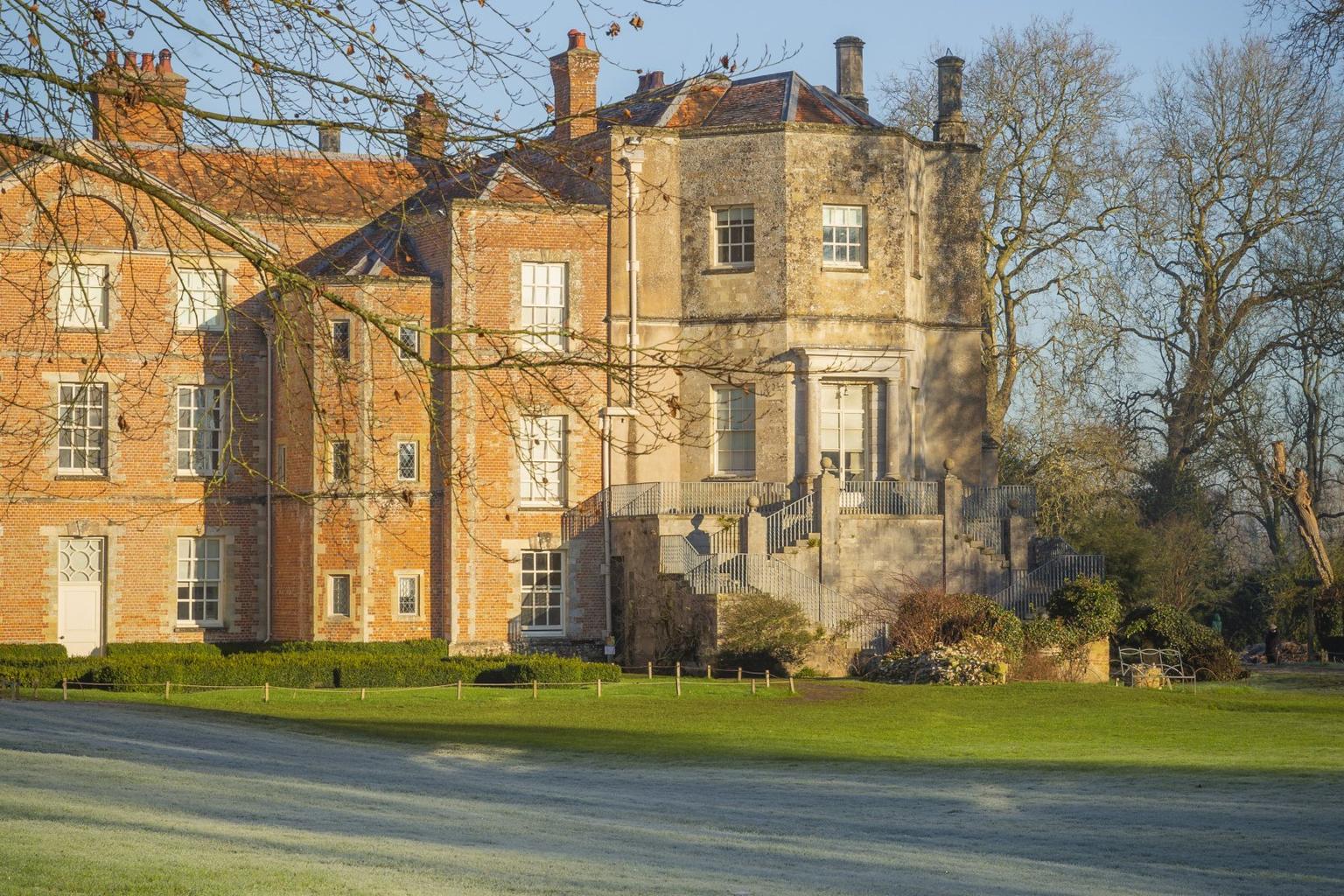A wintery view of a heritage house with frost on the lawn in front