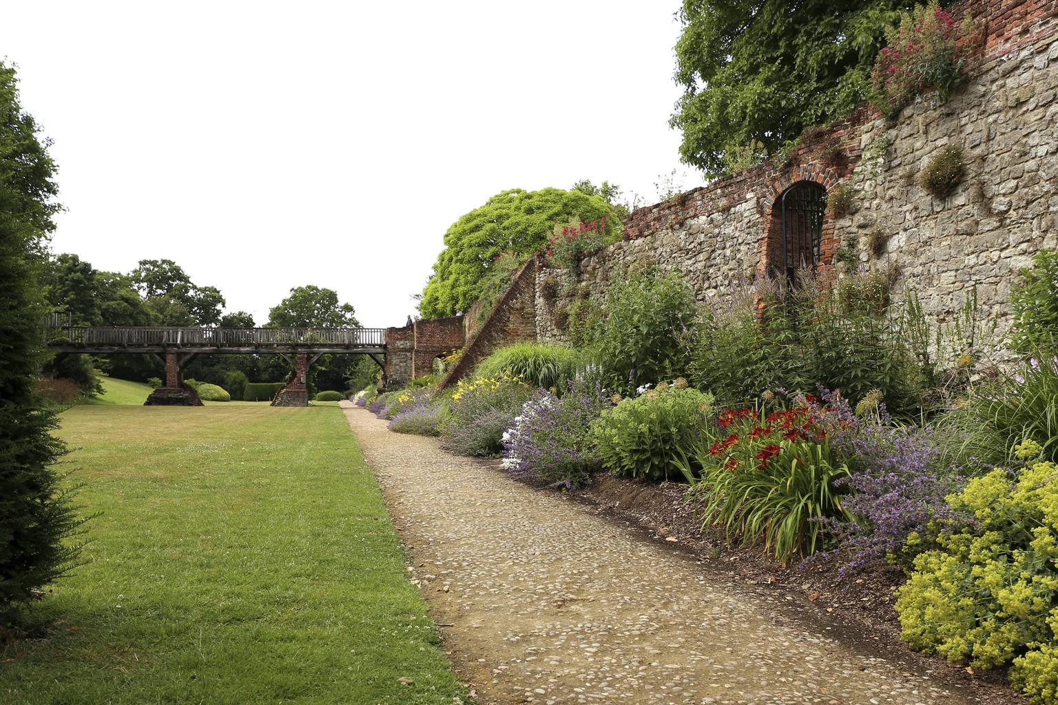 The border of a walled garden, with a bridge in the distance