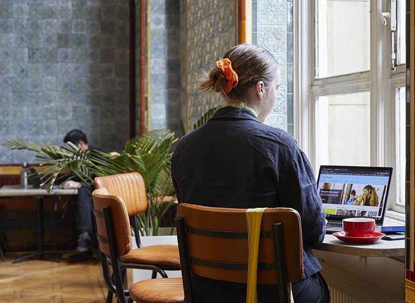 A person browses Art Fund's website sat in a cafe