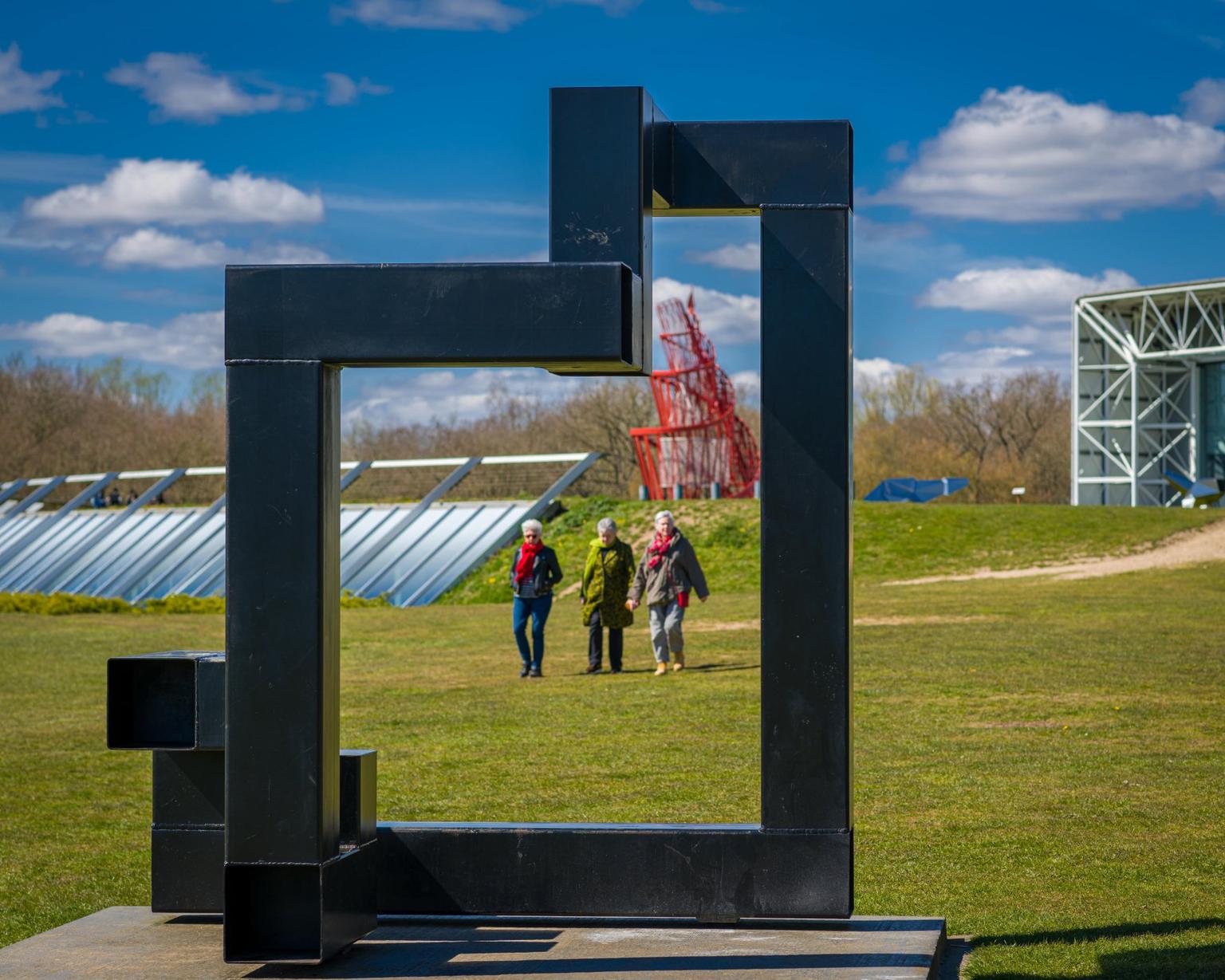 Three people in the background of an outdoor sculpture