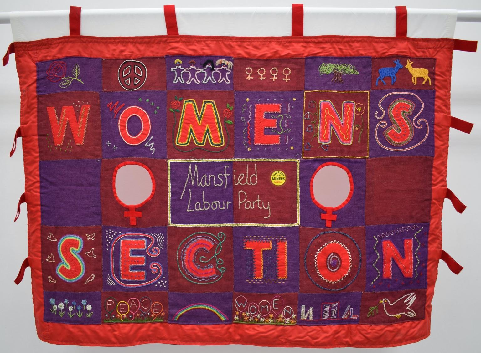 A fabric banner in red purple and yellow reading 'Women's Section' and 'Mansfield Labour Party'