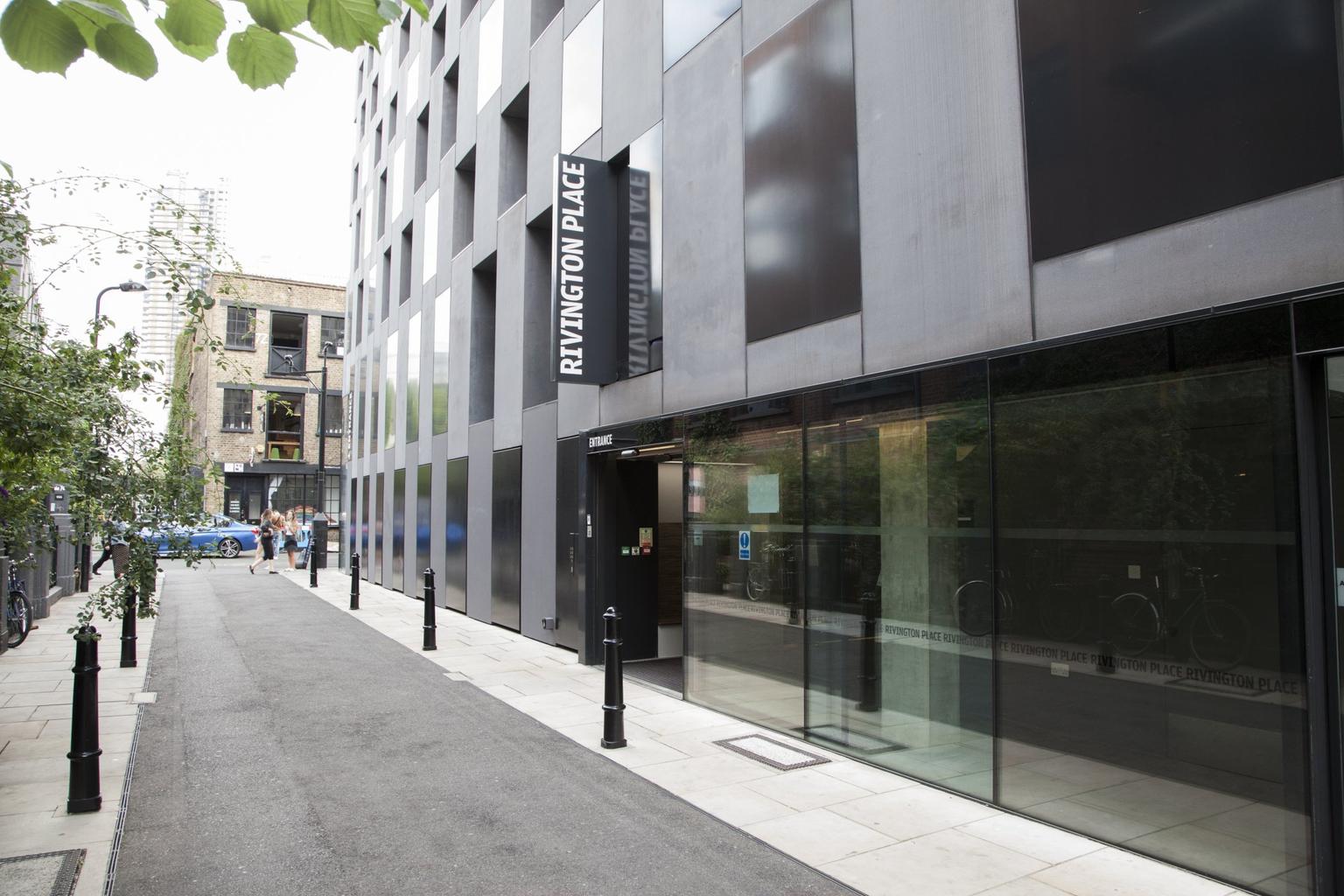 A large grey building with recessed windows, facing onto an empty street