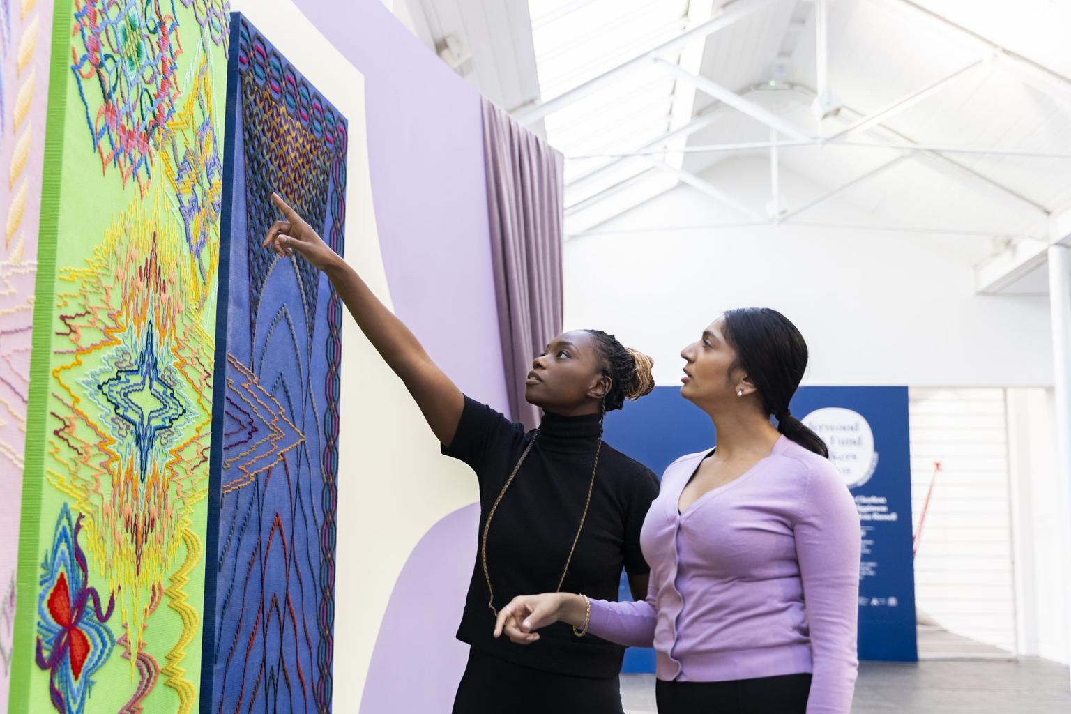 A visitor points out an artwork detail for their colleague