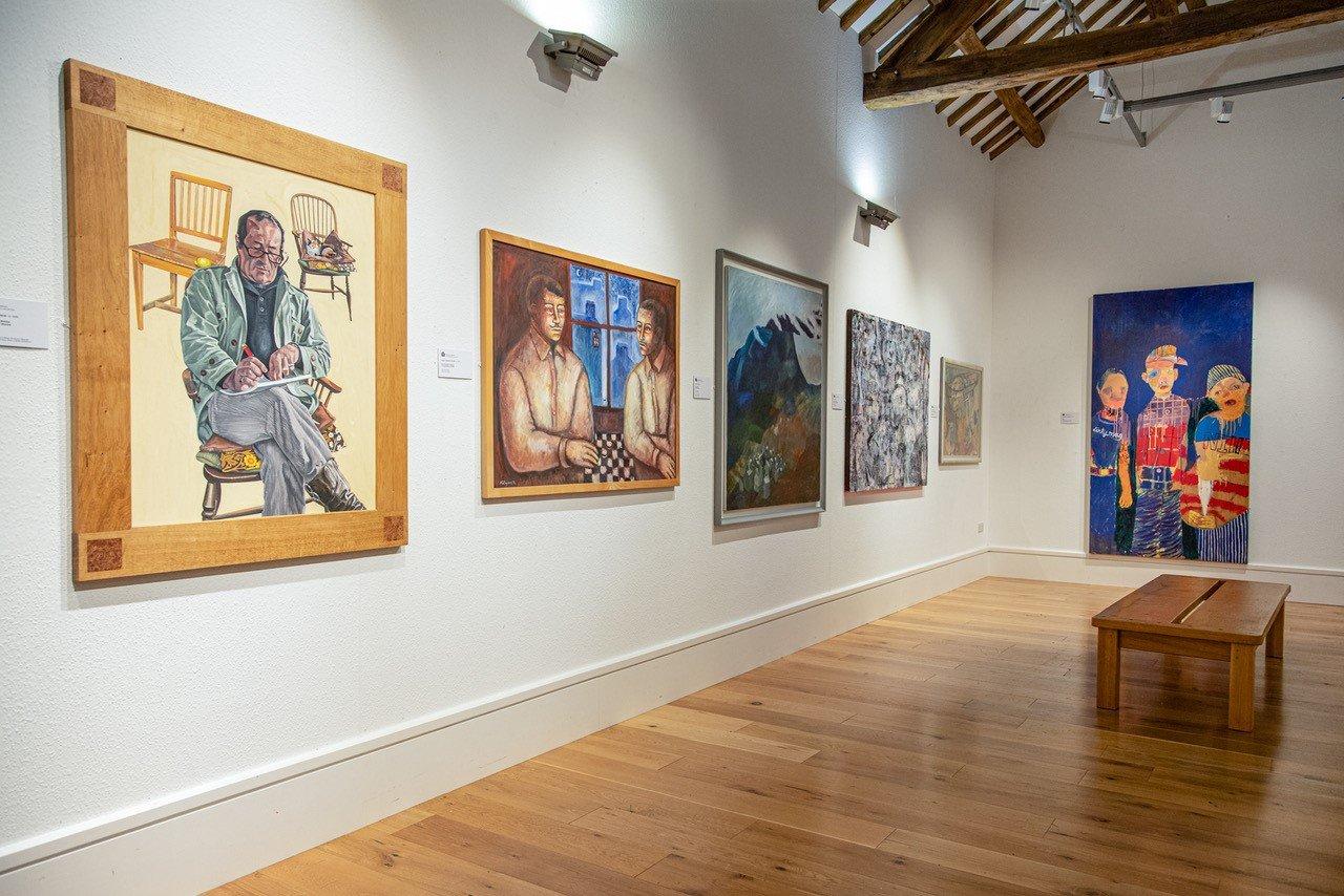 A white walled gallery hung with paintings