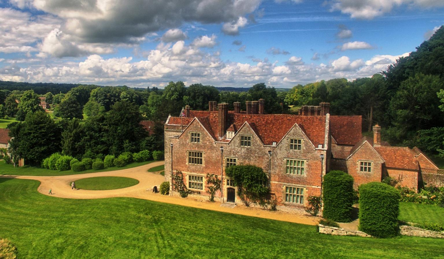 An aerial photo of a historic house with lawns at the front and trees behind