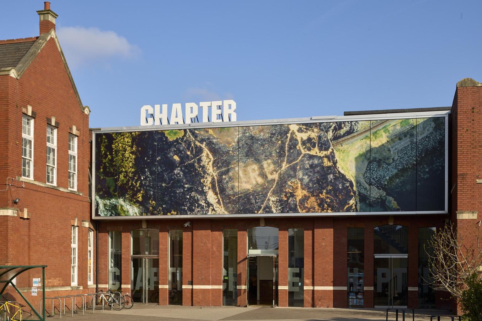 A red brick museum building with a horizontal billboard with an aerial view of the coast.
