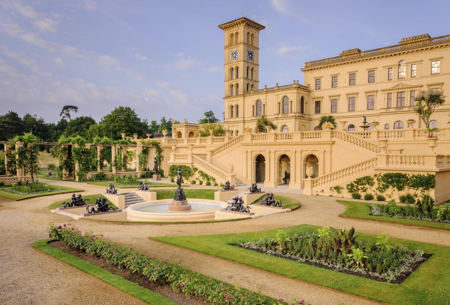 A palatial house with ornamental gardens and fountain in front