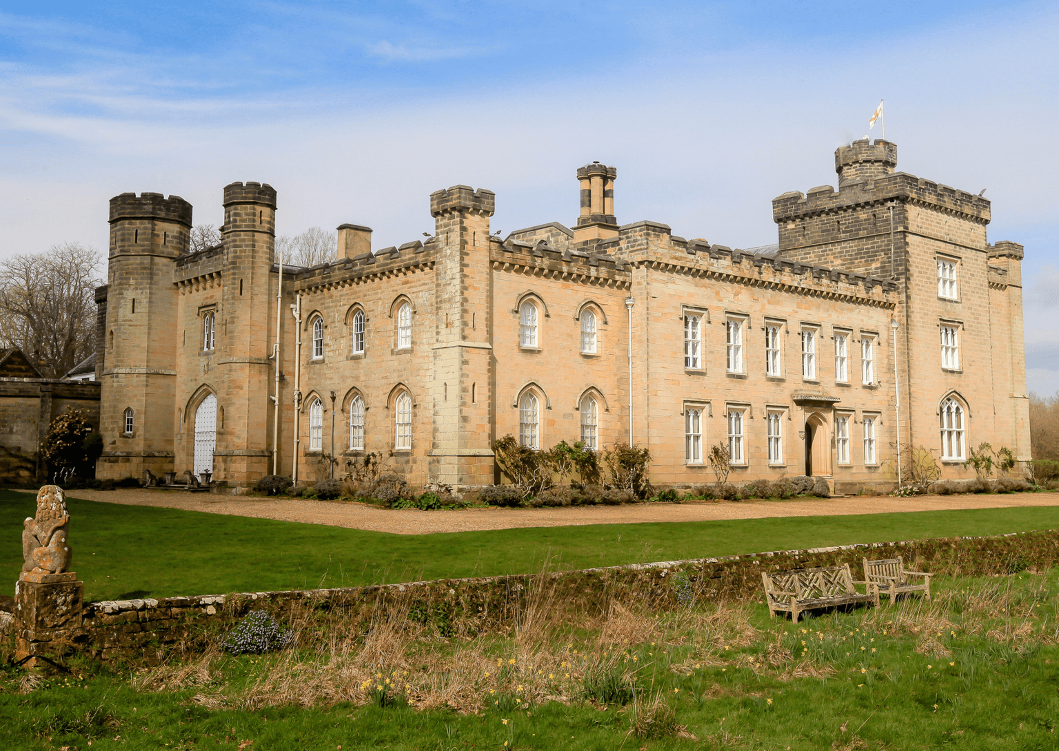 A grand castle behind a low wall, surrounded by lawns
