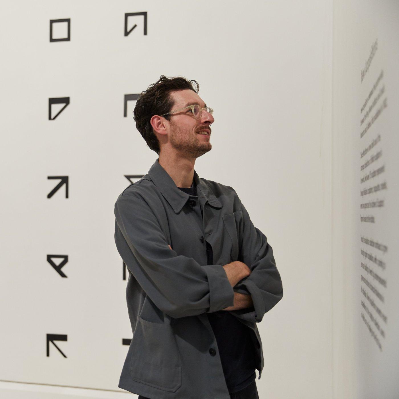 Person in front of an artwork, reading the description of the artwork on a wall
