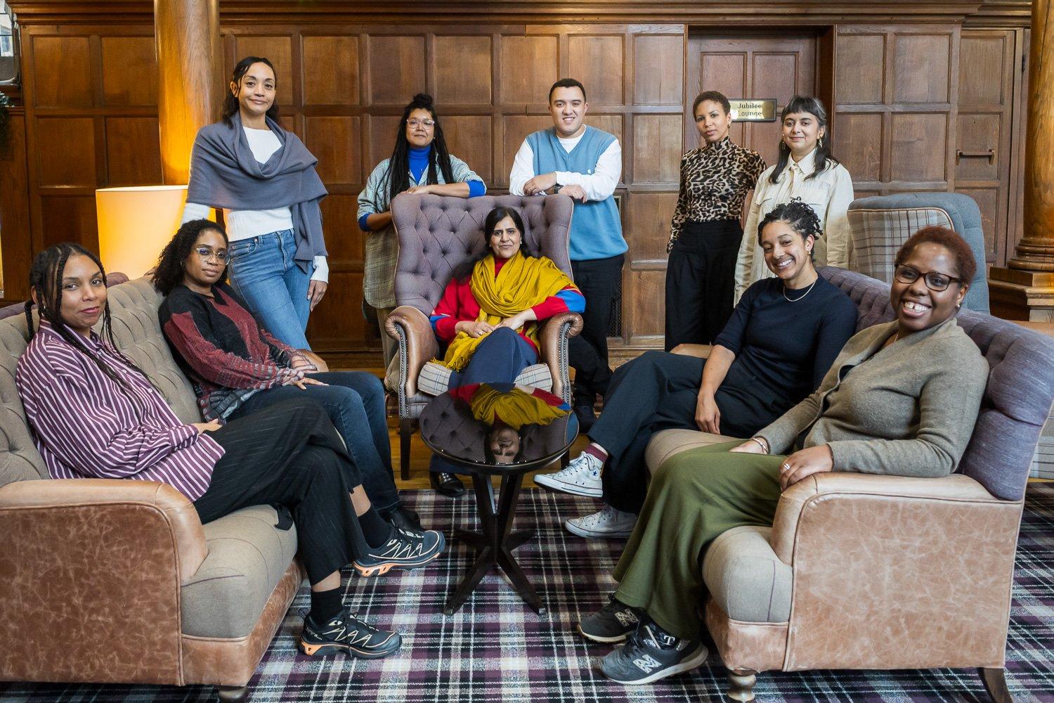 A group of people pose for a portrait in a wood-panelled lounge.
