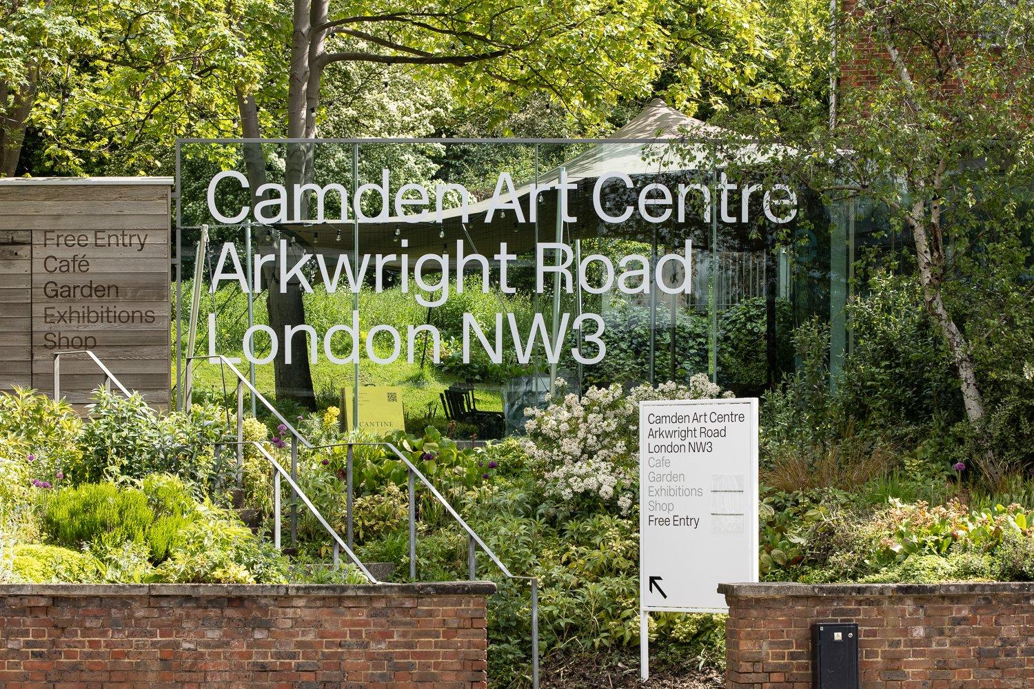 A glass sign for Camden Art Centre amongst greenery next to some steps