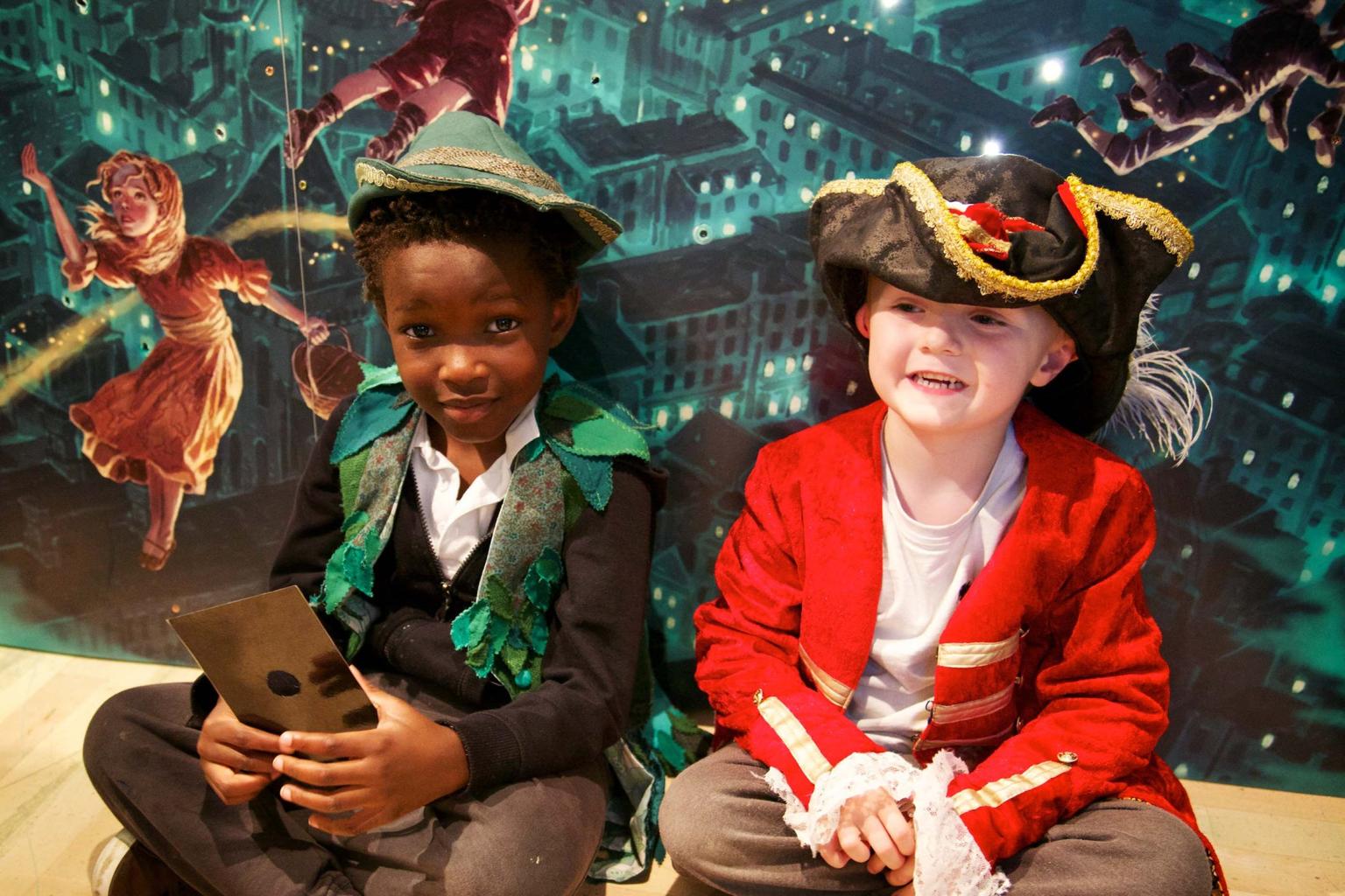 Two boys sitting down in Peter Pan and Captain Hook costumes