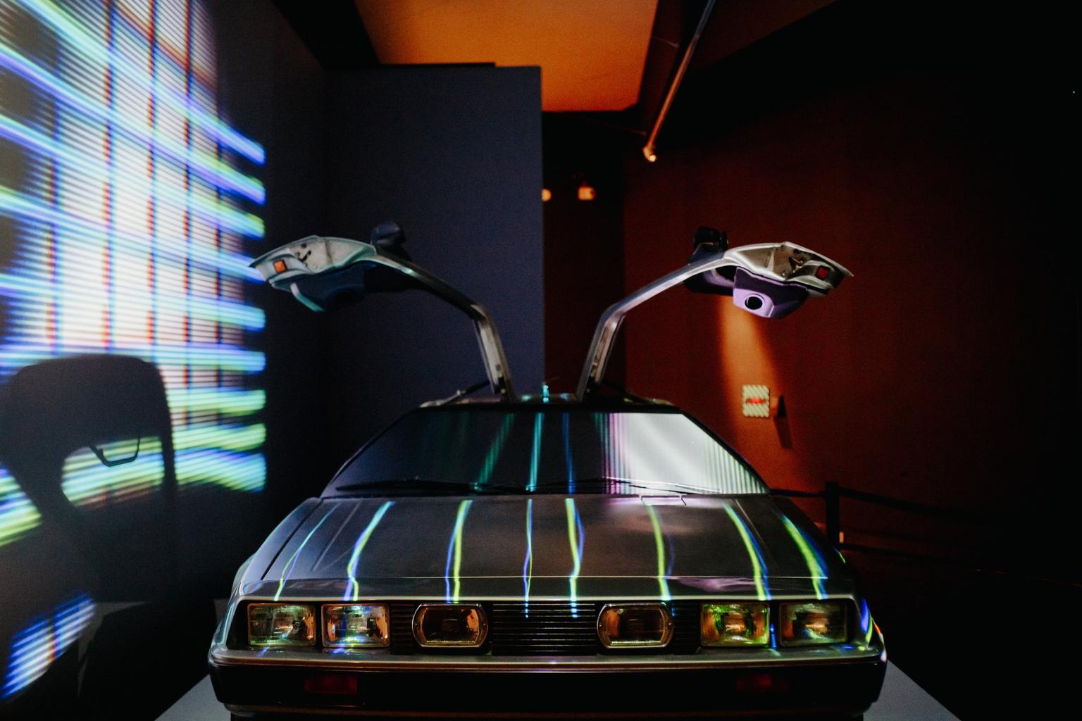 A car in an exhibition space with its side doors open above it