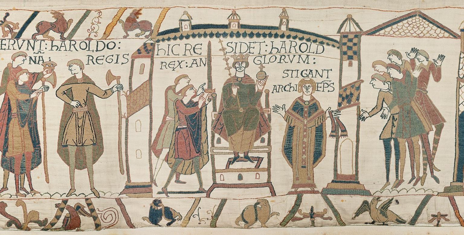 Medieval tapestry panel showing the coronation of William the Conqueror, who sits on a throne while robed figures watch on.
