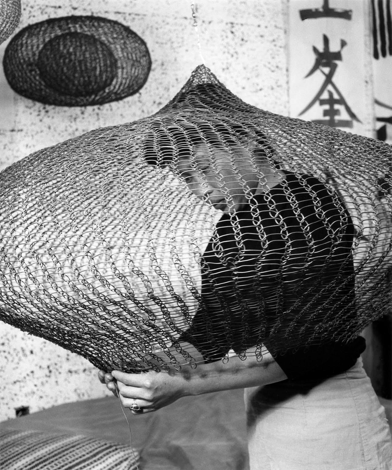 Ruth Asawa working on a wire sculpture at her Saturn Street home, San Francisco, 1957.
